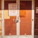 A locked and boarded school entrance with no trespassing signs emphasizing safety rules.