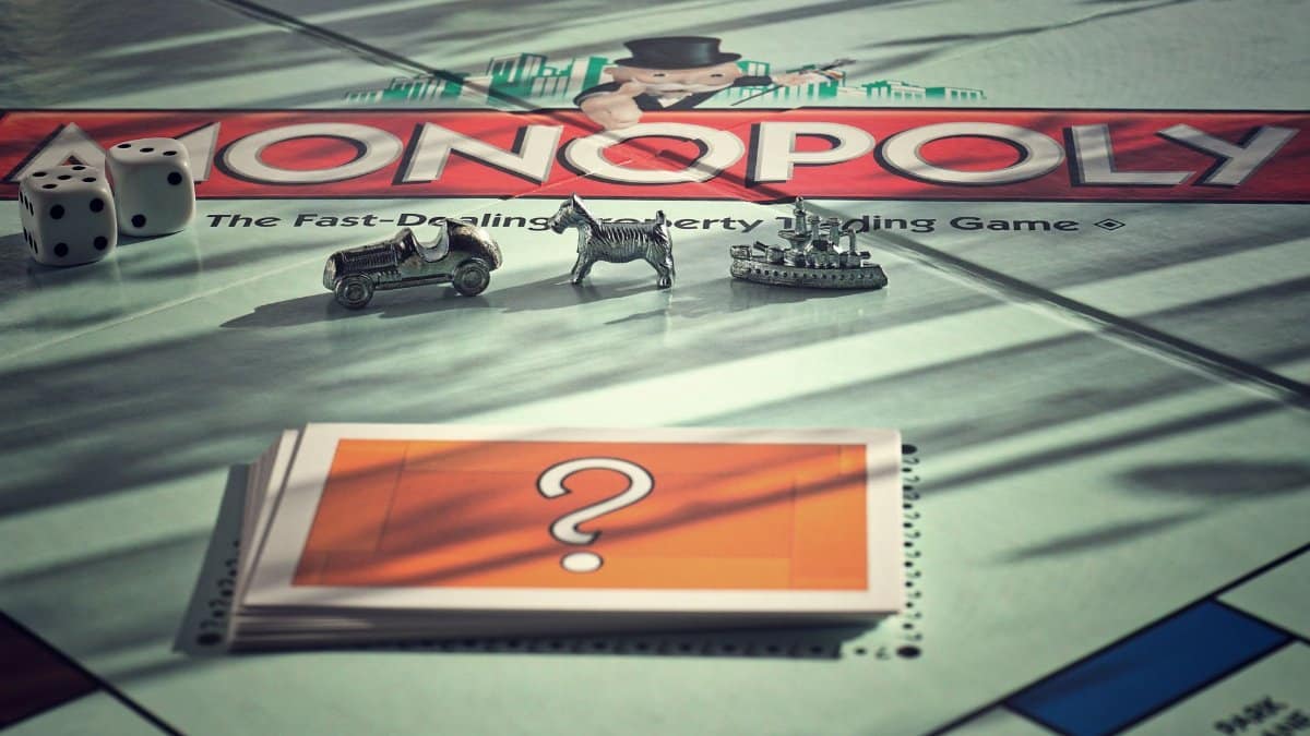 Close-up of Monopoly board game with metal tokens and dice in warm light.