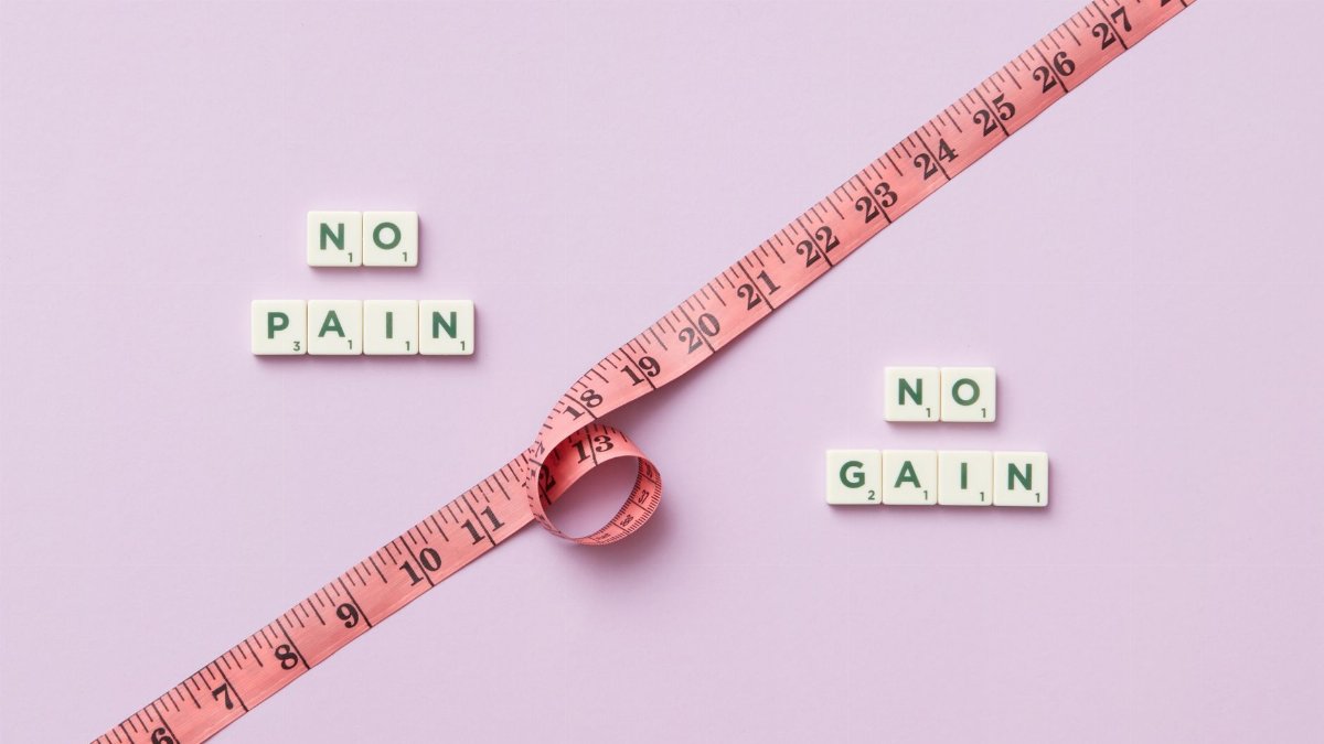 Pink tape measure with 'No Pain No Gain' spelled in Scrabble tiles on pink background.