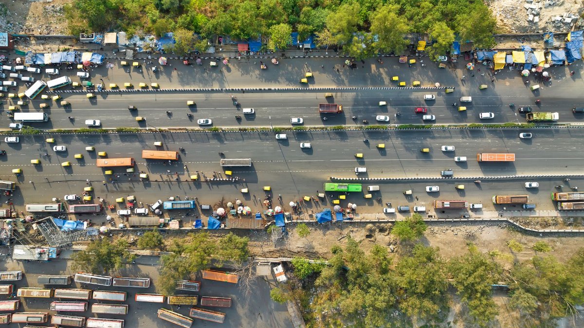 Aerial view of a busy highway with vehicles and stalls, showcasing urban life.
