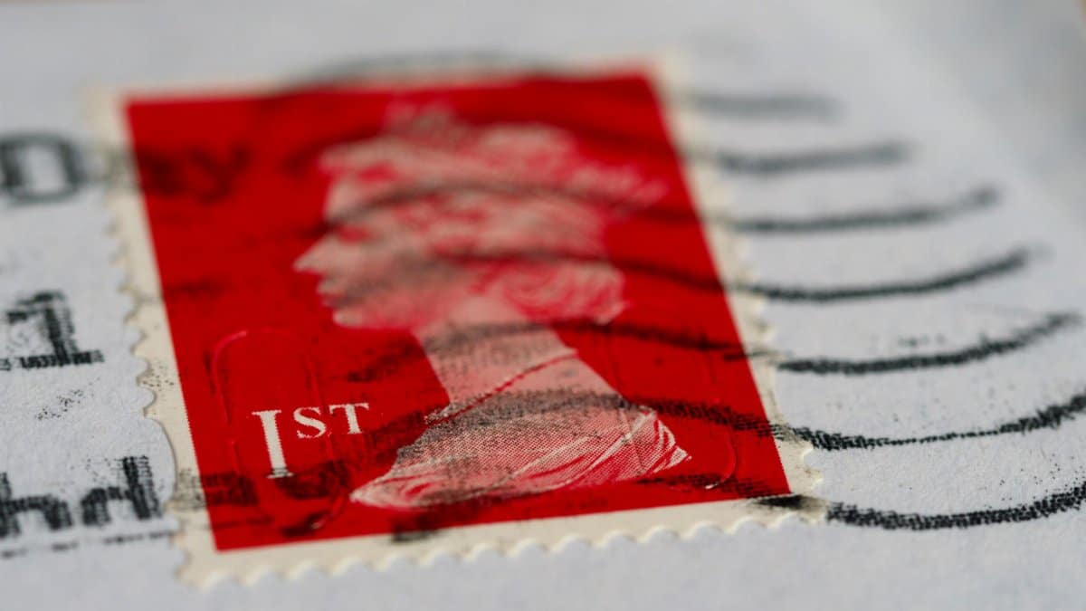 Detailed view of a red first-class postage stamp with a visible postmark.