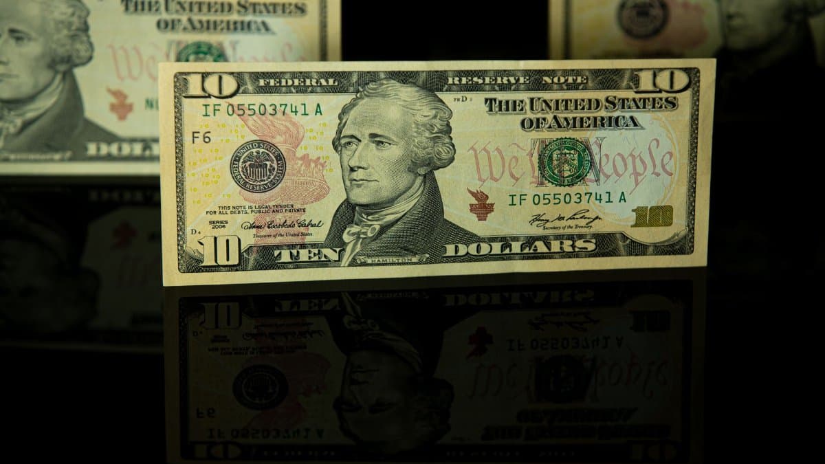 Detailed image of a ten dollar bill with dark reflective background.