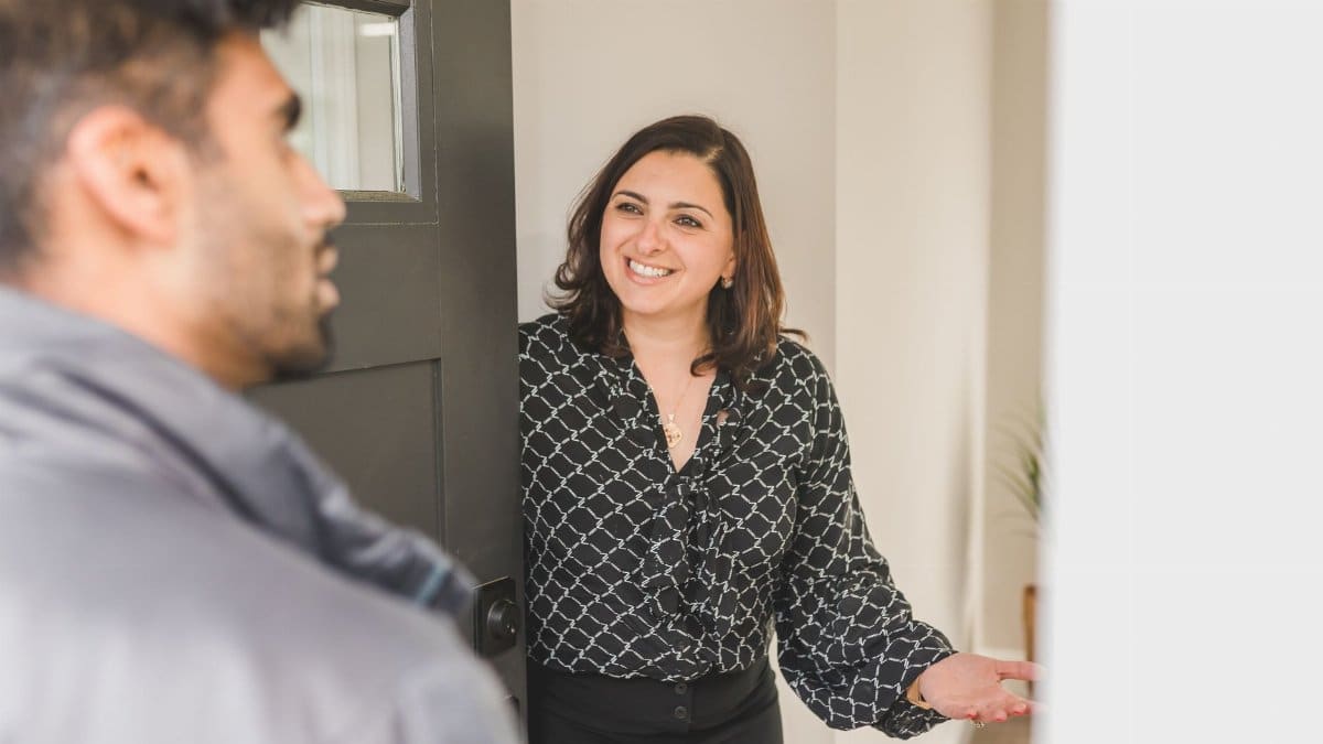 Friendly real estate agent greets client at the door, showcasing modern hospitality.