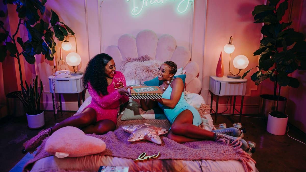 Two women enjoy a festive moment exchanging gifts in a cozy, decorated room.