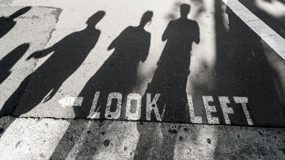 Shadows of pedestrians cast on crosswalk with 'Look Left' sign in Sydney.