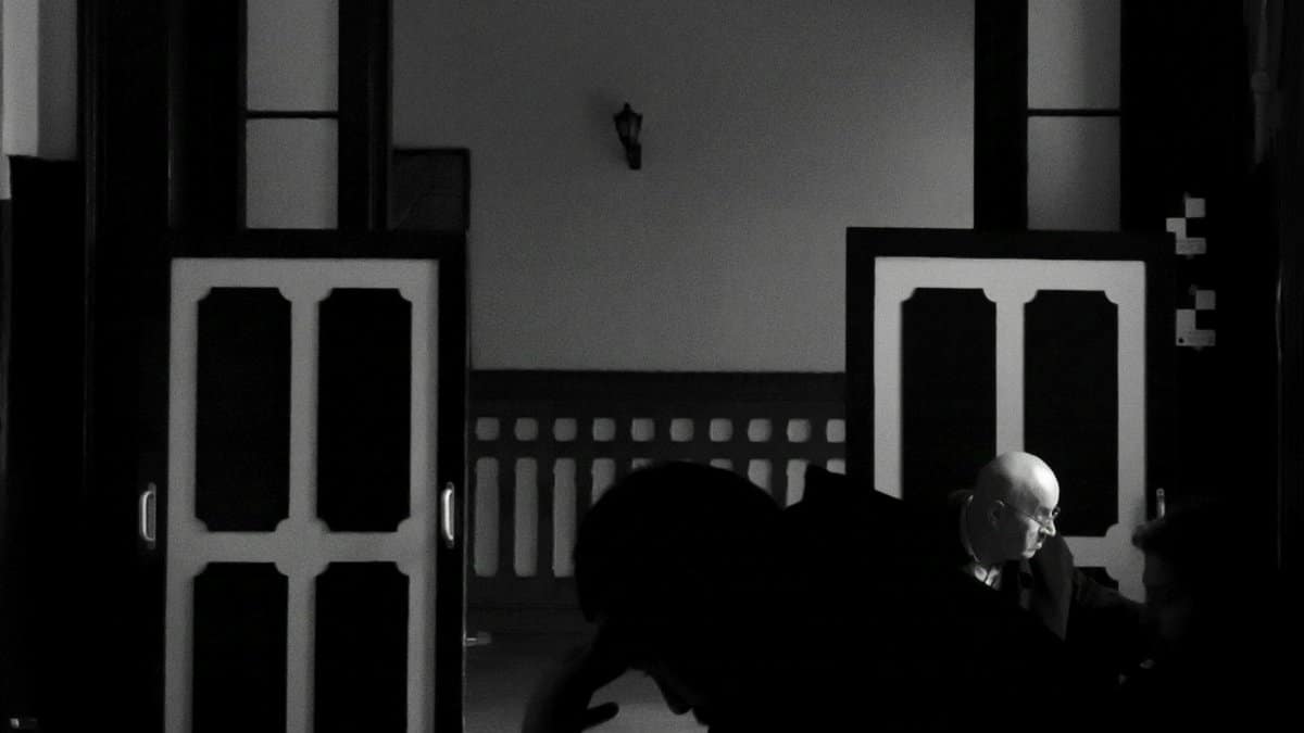 Black and white photo showing silhouettes of people in a dimly lit room, İstanbul.