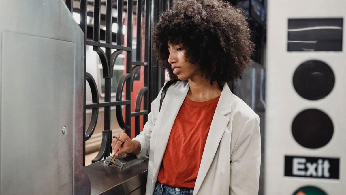 Young woman navigating a subway turnstile with a card in an urban station.