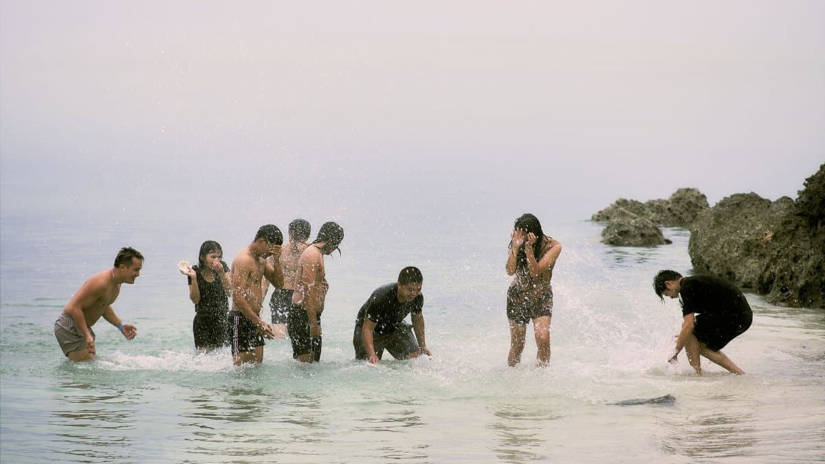 A group of friends splashing water and having fun at the beach on a bright day.