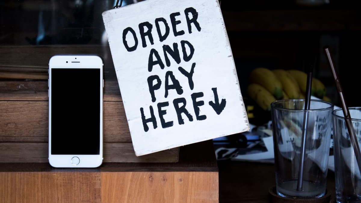 A phone next to an 'Order and Pay Here' sign in a cozy indoor setting, perfect for business use.