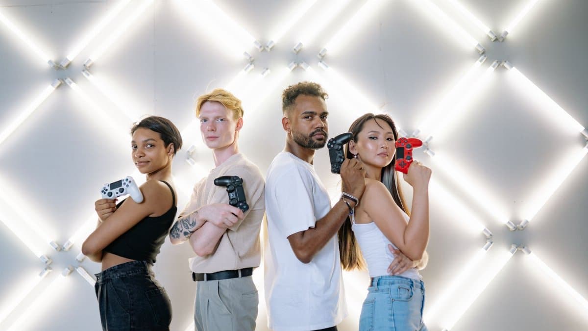 Four diverse friends posing confidently with game controllers against a modern LED backdrop.