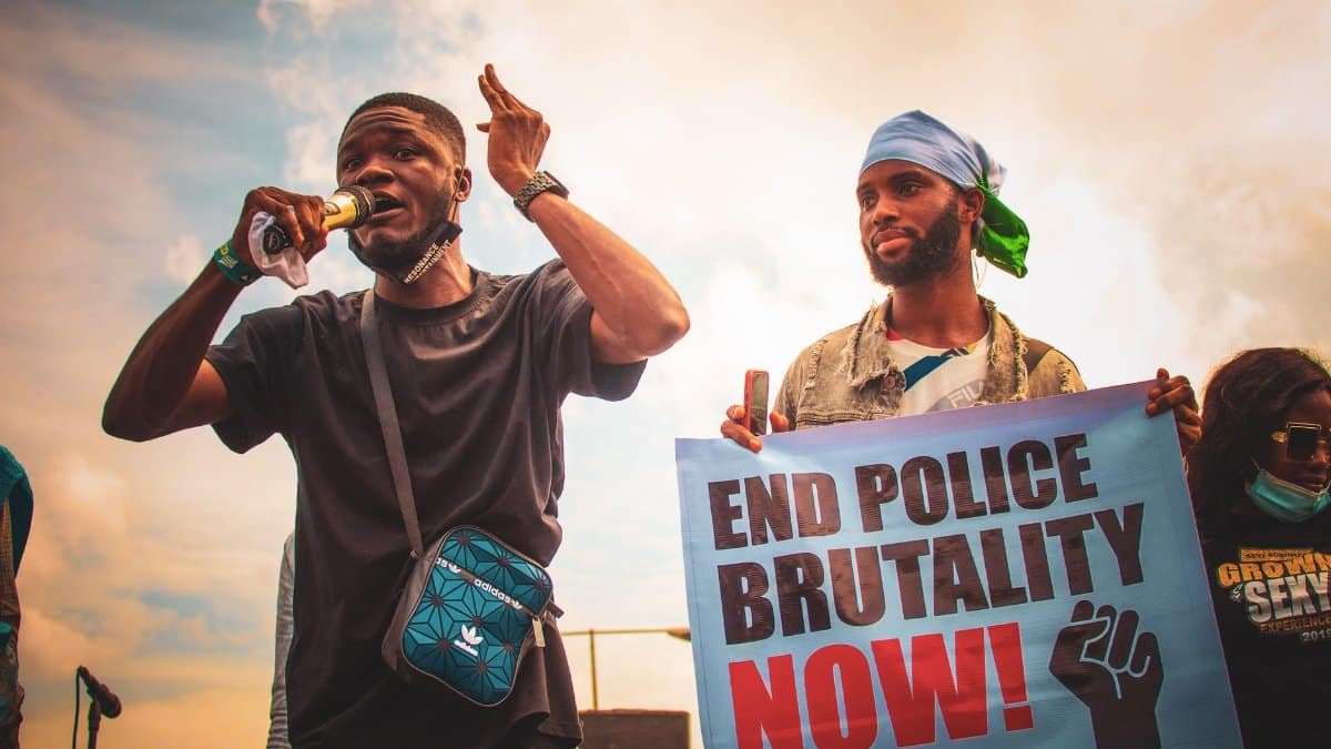 Protesters hold signs and speak during an outdoor rally against police brutality in Nigeria.