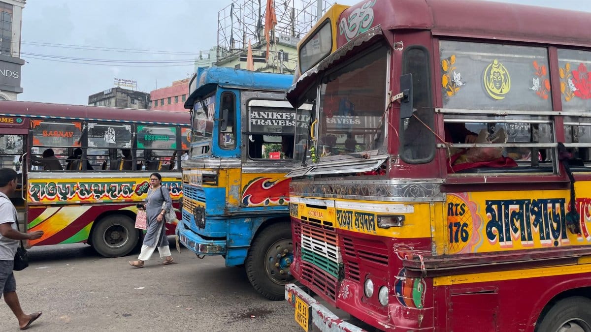 Vibrant buses on a bustling Kolkata street with local commuters and detailed designs.