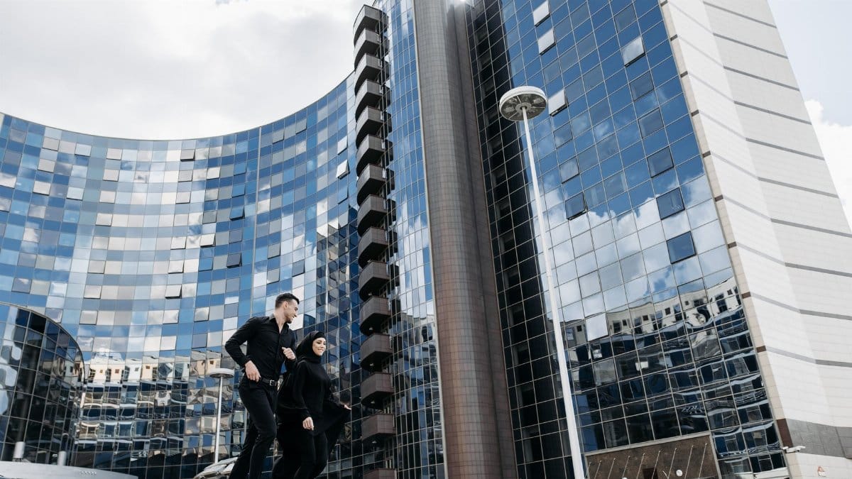 Contemporary building facade with a stylish couple walking, showcasing modern urban life.
