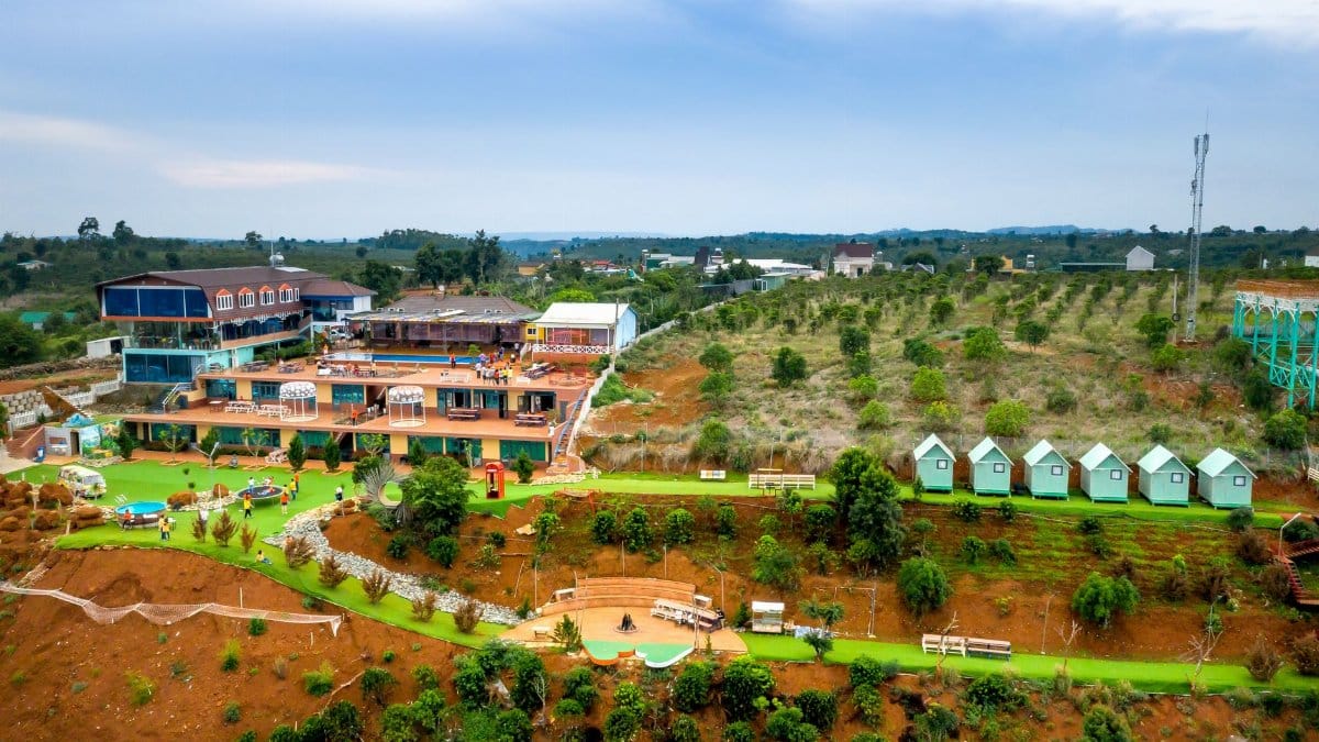 Stunning aerial view of a colorful rural resort amidst lush countryside and clear blue skies.