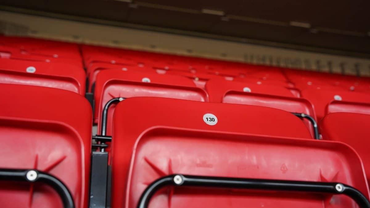 Close-up of numbered red stadium seats in an empty arena, highlighting seats at a famous stadium.