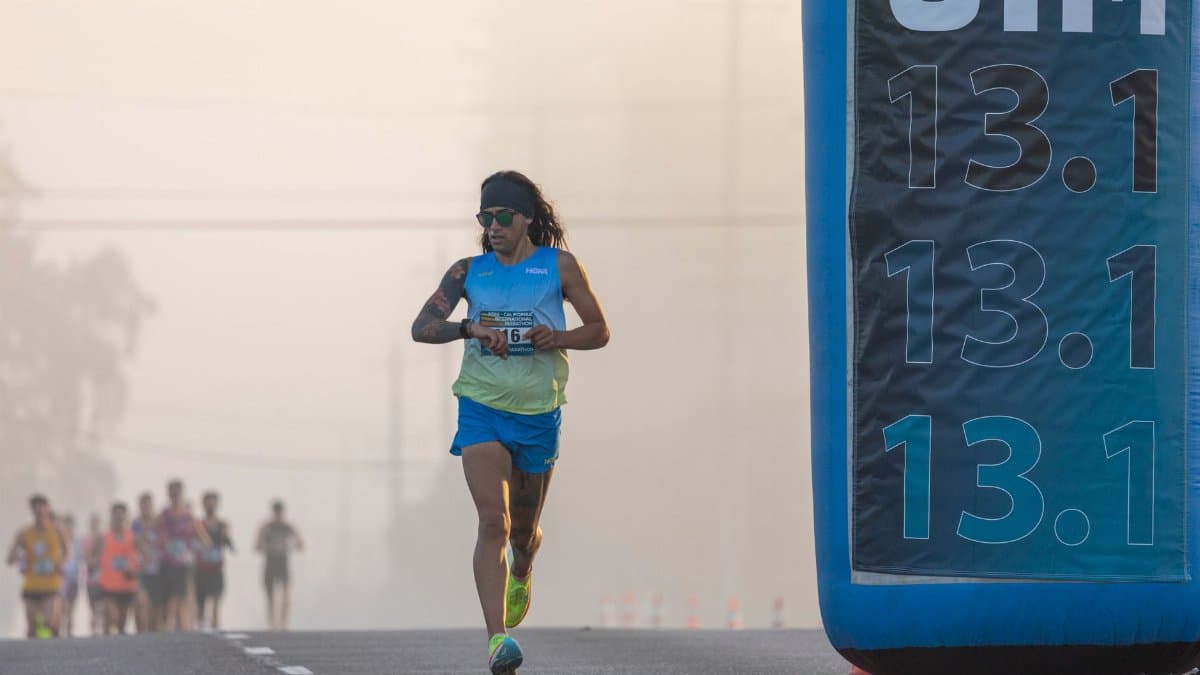 Focused runner at California International Marathon with distance marker in soft light.