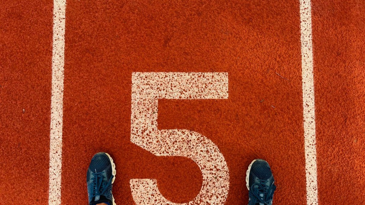 Runner's feet on track lane 5 at the finish line, symbolizing completion and success.