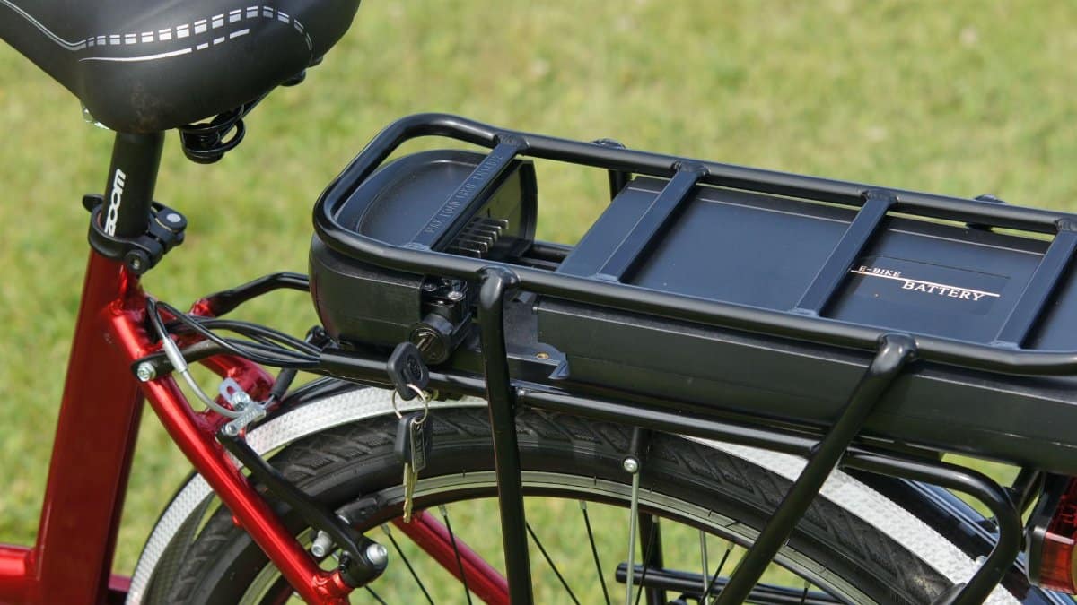 Detailed view of an electric bicycle battery mounted on a rear rack, highlighting the key-lock mechanism.