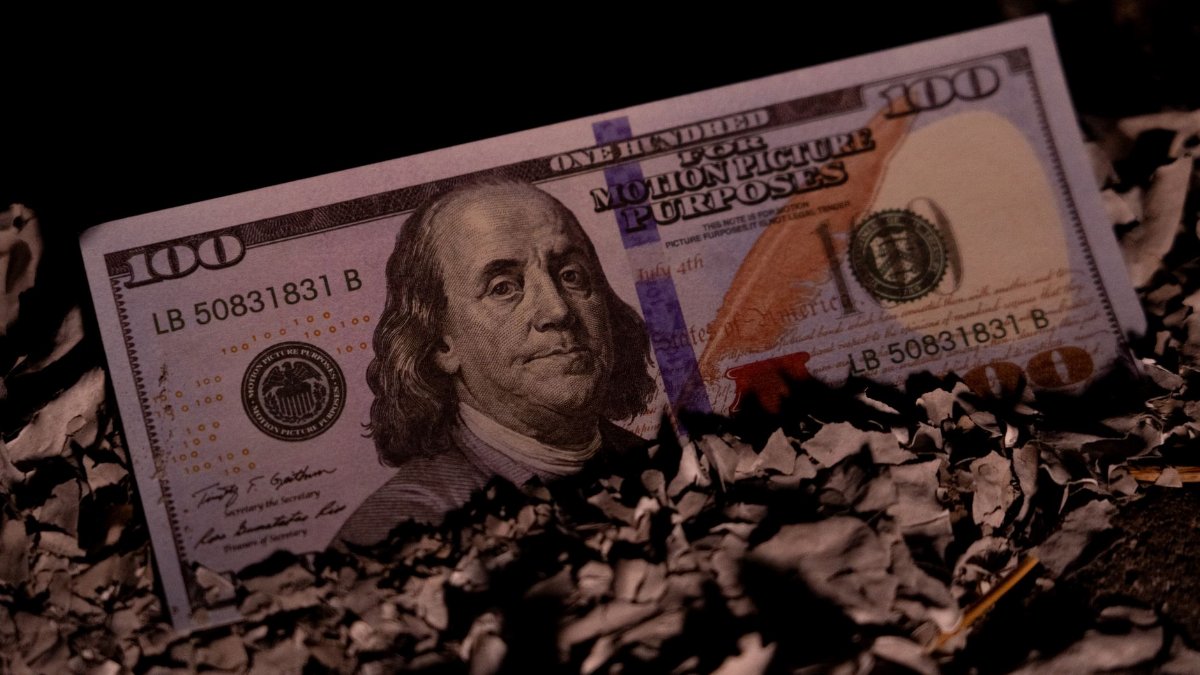 Close-up of a realistic fake $100 bill labeled 'For Motion Picture Purposes' on shredded paper.