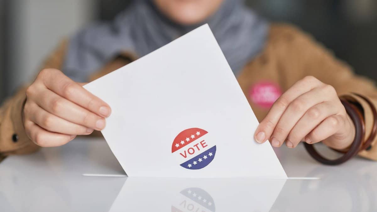 Close-up of hands holding a vote ballot, symbolizing election participation.