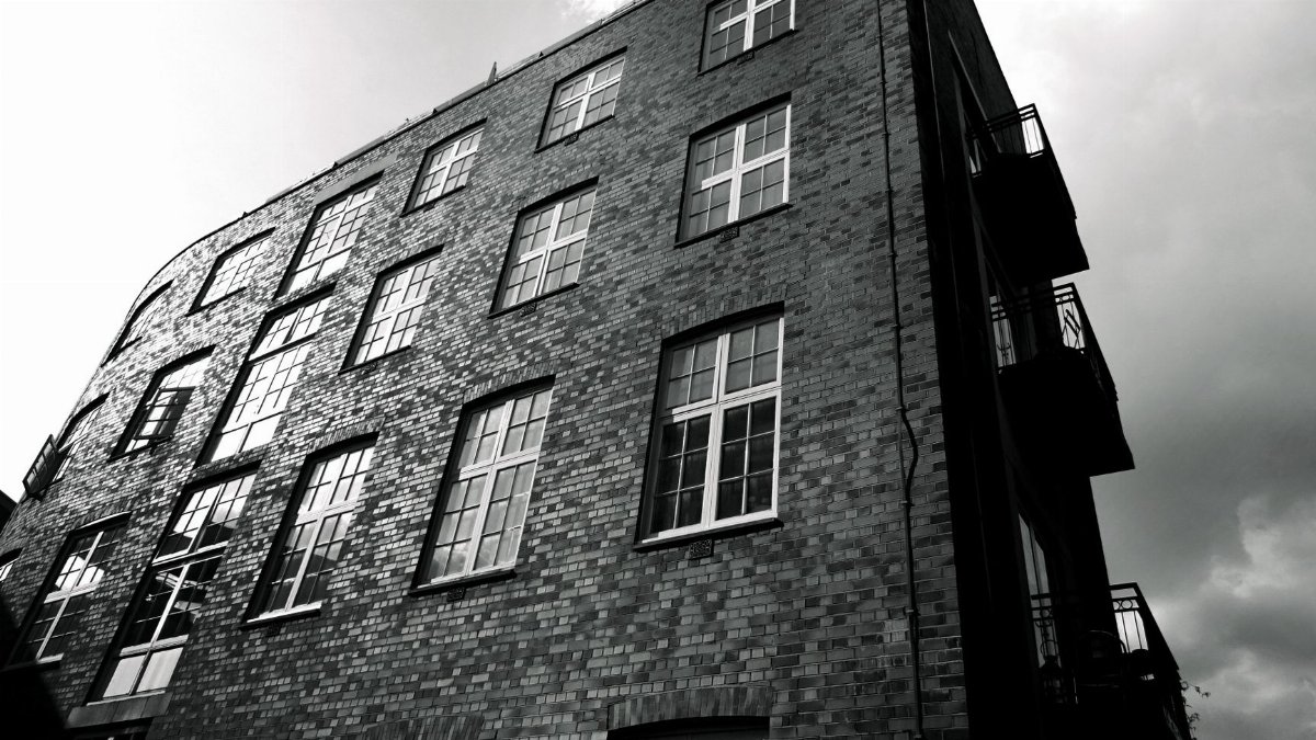 Low angle monochrome view of a brick building emphasizing geometry and contrast.