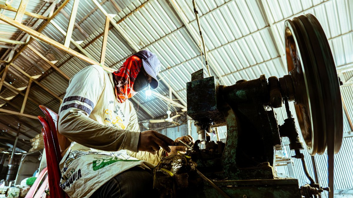 Industrial worker using vintage machinery inside a workshop, highlighting manual labor and craftsmanship.