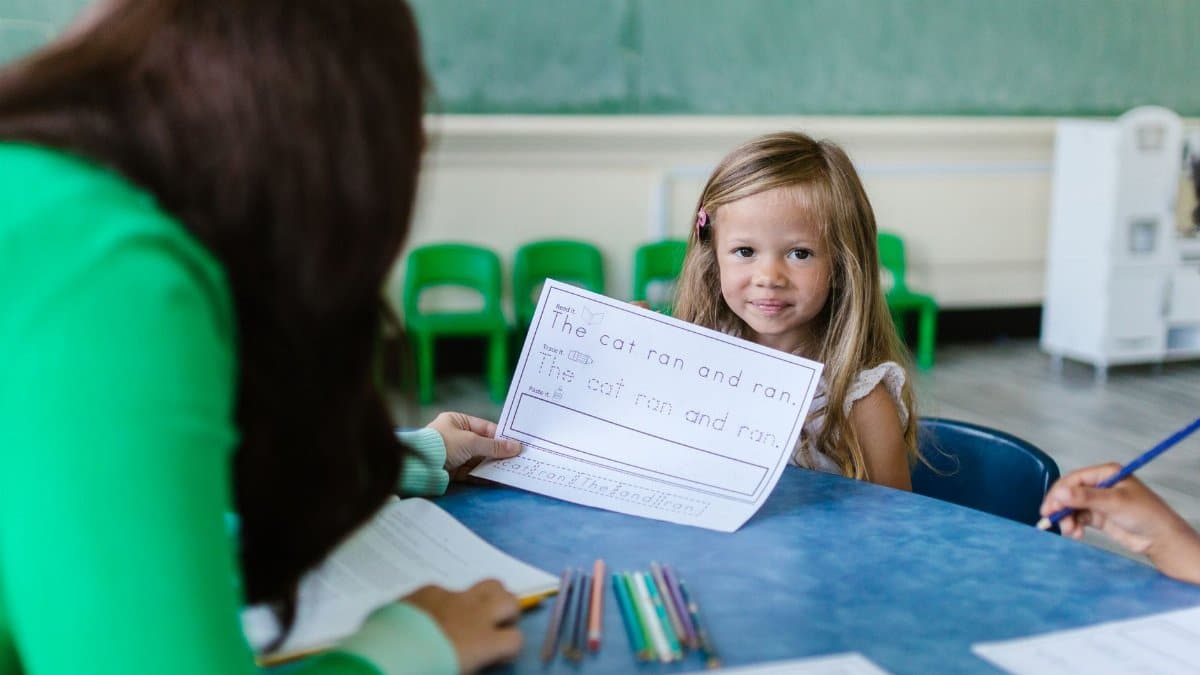 A young girl participates in an engaging classroom activity with her teacher.