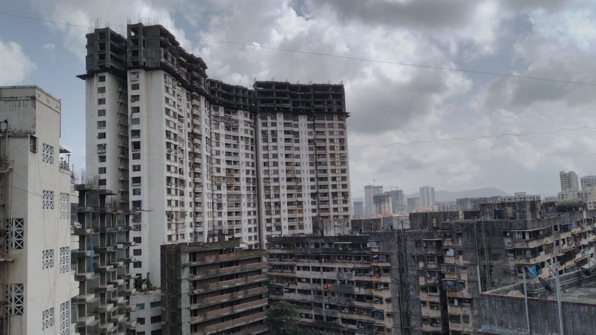 High-rise urban buildings under a dramatic cloudy sky, captured from an aerial perspective.