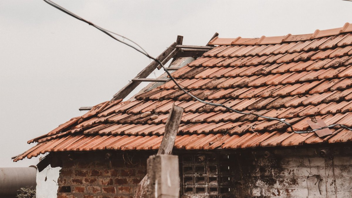 An old rural house with a damaged clay tile roof in Chennai, India, showing signs of decay.