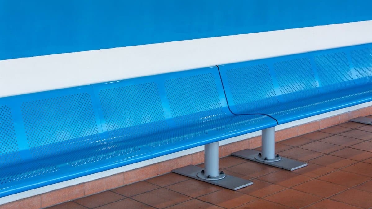 Sleek metallic blue bench in a bright, empty waiting room, highlighting minimalist design.