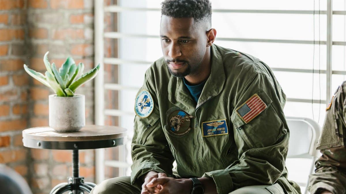 Thoughtful military veteran in uniform listening intently indoors.