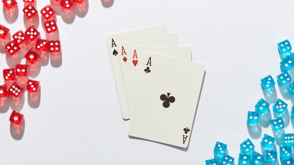 Four aces surrounded by red and blue dice on a white surface, perfect for poker or casino themes.