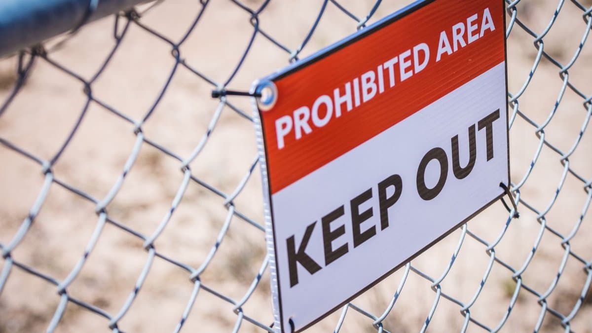 Close-up of a 'Prohibited Area' and 'Keep Out' sign on a chain link fence.