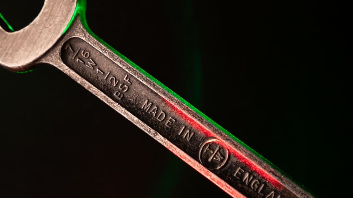 Detailed close-up of a steel wrench with inscription, illuminated with red and green lighting.