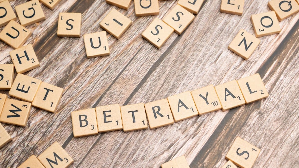 Wooden letter tiles spelling 'Betrayal' on a rustic wooden surface, conveying themes of deceit and dishonesty.