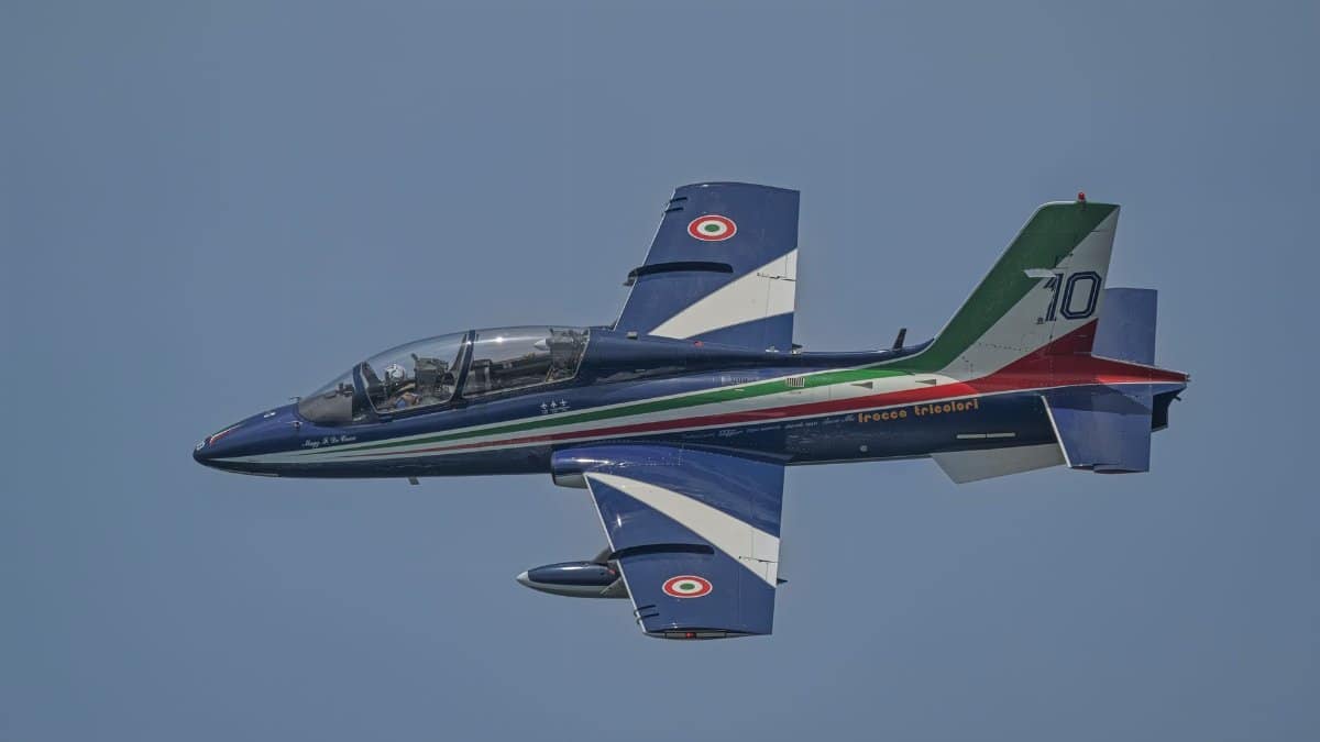 Italian Air Force aerobatic jet with tricolor markings soaring in clear sky.