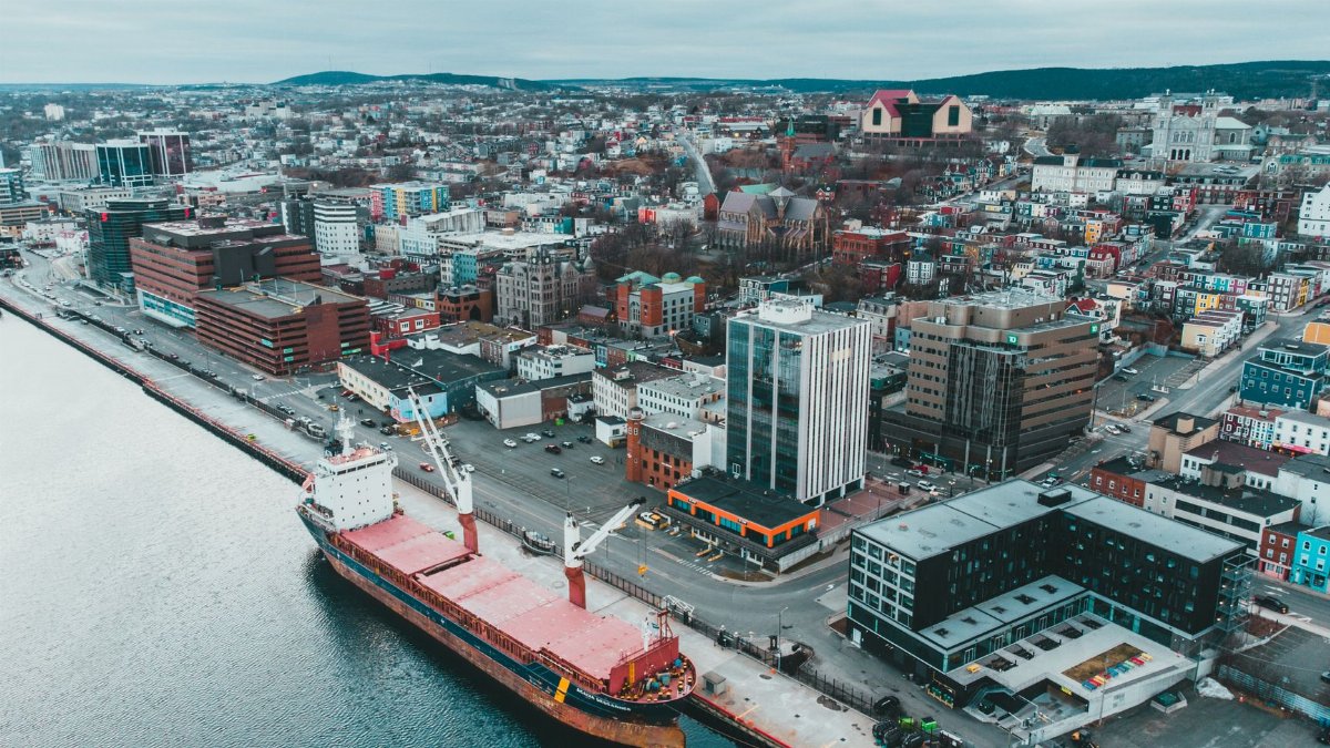 Scenic aerial view of harbor with ship moored in port of city under cloudy sky