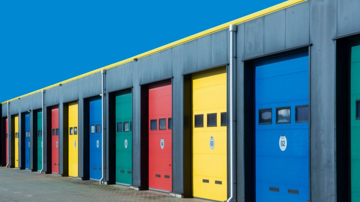 Vibrant row of industrial garage doors in blue, red, yellow, and green, perfect for commercial use.