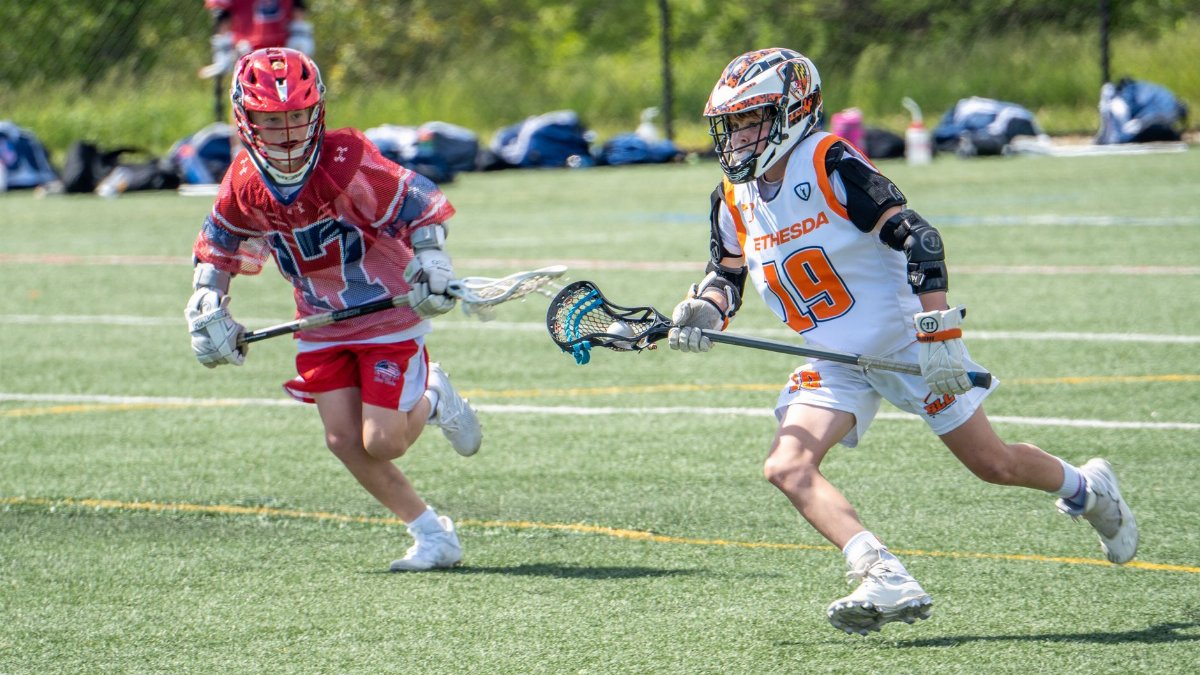 Two young lacrosse players in action during a match on a sunny day in Columbia, MD.