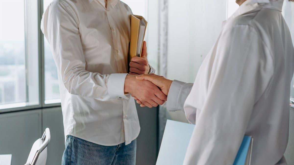 Two professionals shake hands indoors, symbolizing agreement or partnership in business.