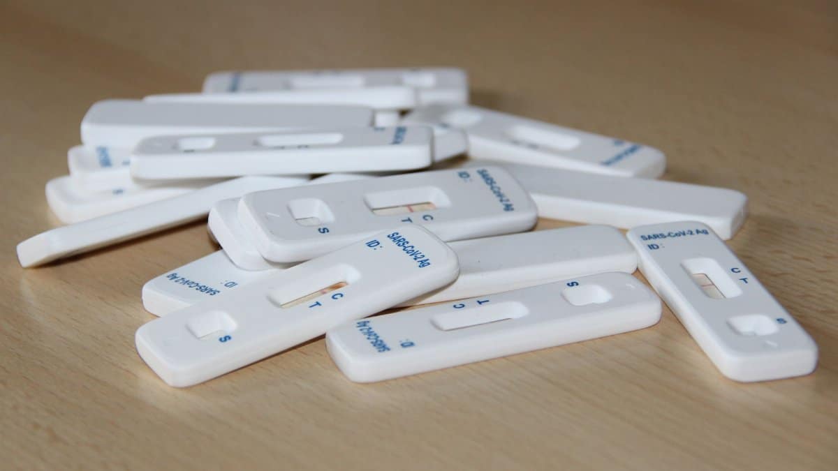 Close-up of several Covid-19 rapid test kits scattered on a wooden table.