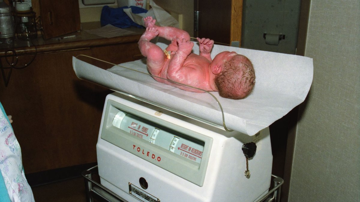 Newborn baby being weighed on a hospital scale, documenting the first moments of life.