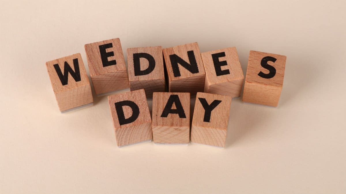 Wooden blocks arranged to spell Wednesday on a plain beige background, ideal for calendar or weekday concepts.