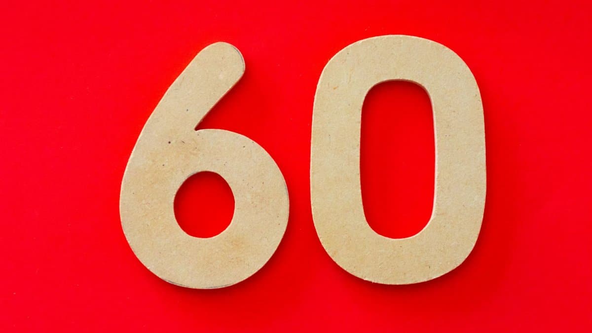 Wooden cutout of the number 60 displayed on a vibrant red background, ideal for milestones or celebrations.