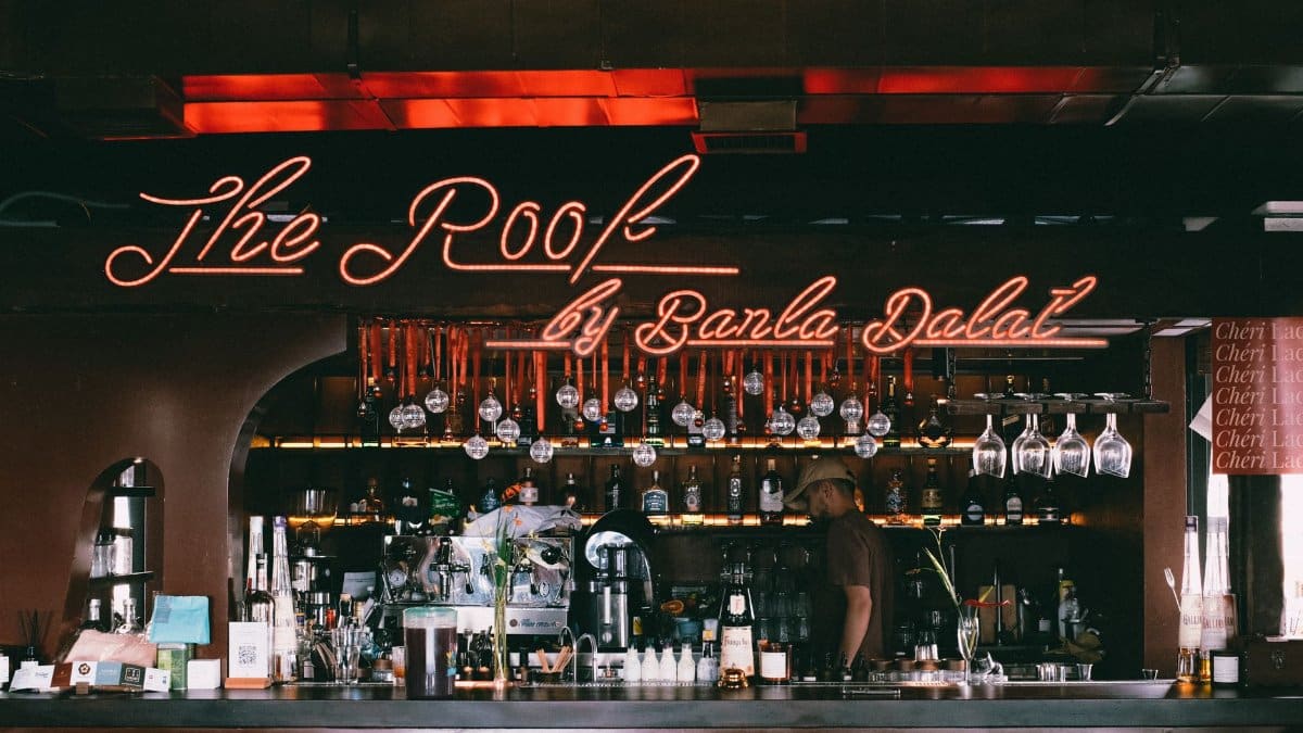 Warm atmosphere in a bar with neon lighting and a variety of liquor bottles on display.