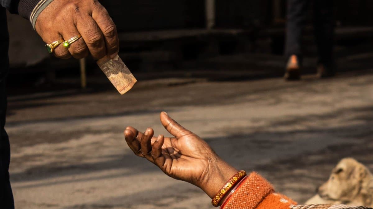 A detailed capture of a street donation with an outstretched hand receiving money.