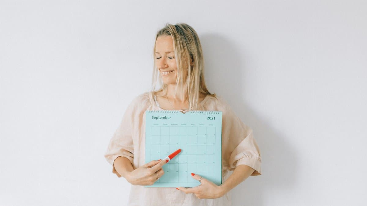 Smiling woman points at a date on a calendar, conveying excitement and anticipation.