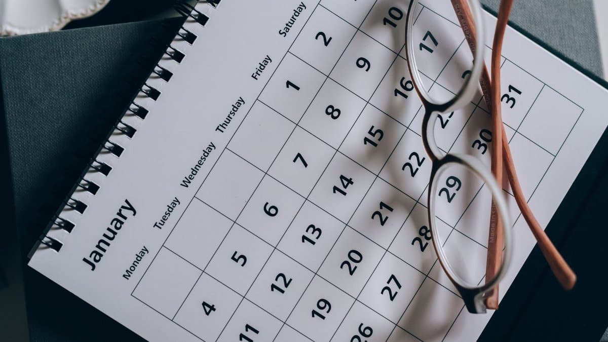 A close-up of a January calendar with eyeglasses on a table, emphasizing planning and organization.
