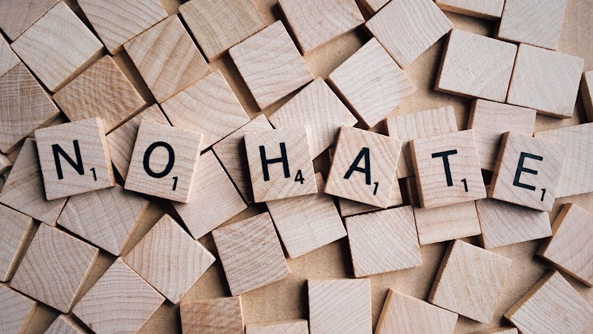 Overhead shot of wooden scrabble tiles forming the phrase 'No Hate', emphasizing a message of inclusivity.