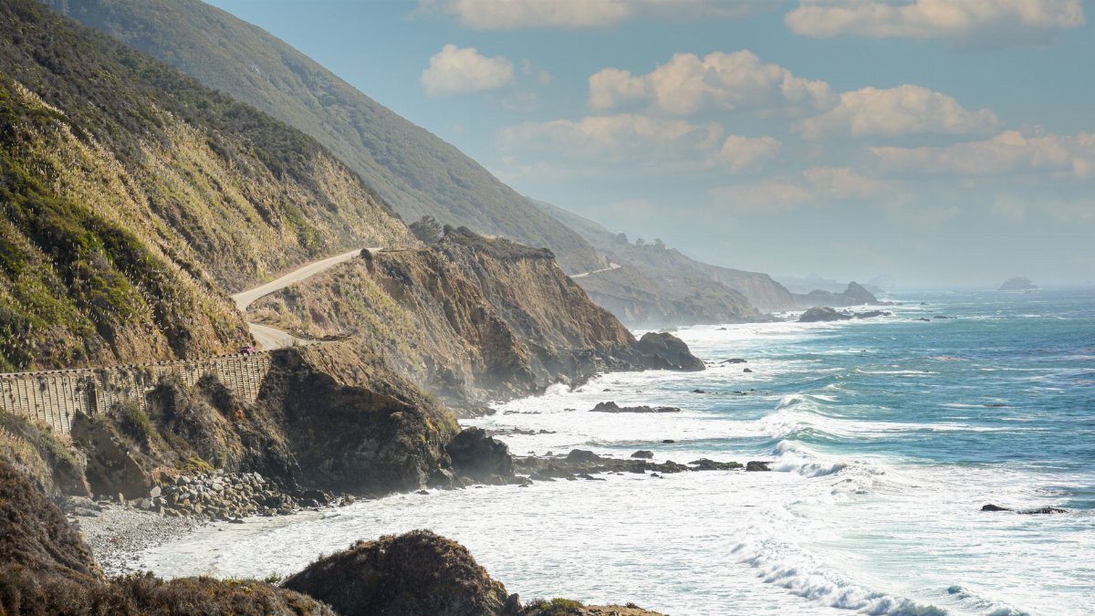 Captivating view of California's coastal highway along the rocky shore with ocean waves crashing.